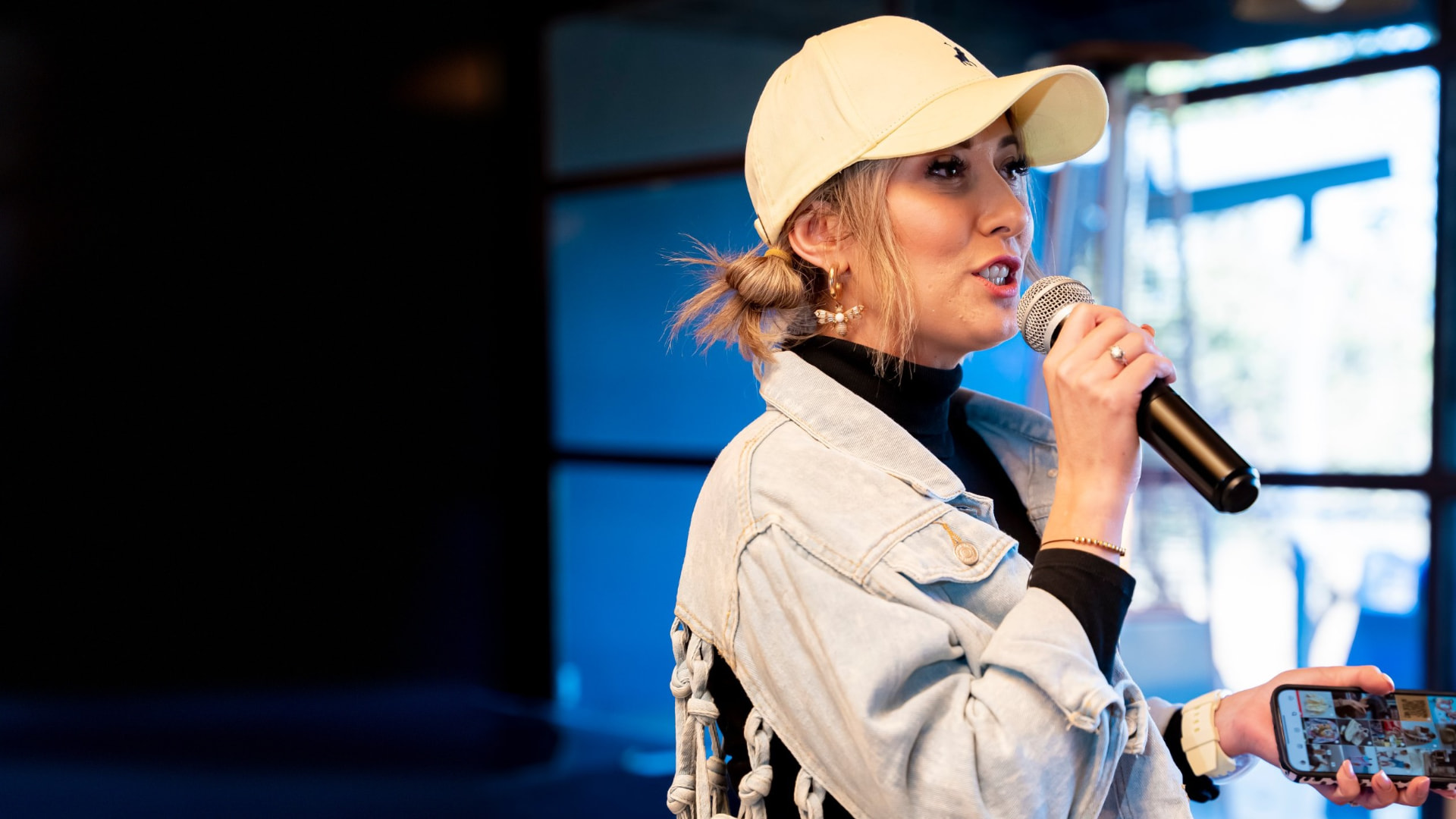 Danielle Steynvaardt speaking into a microphone while holding up her phone